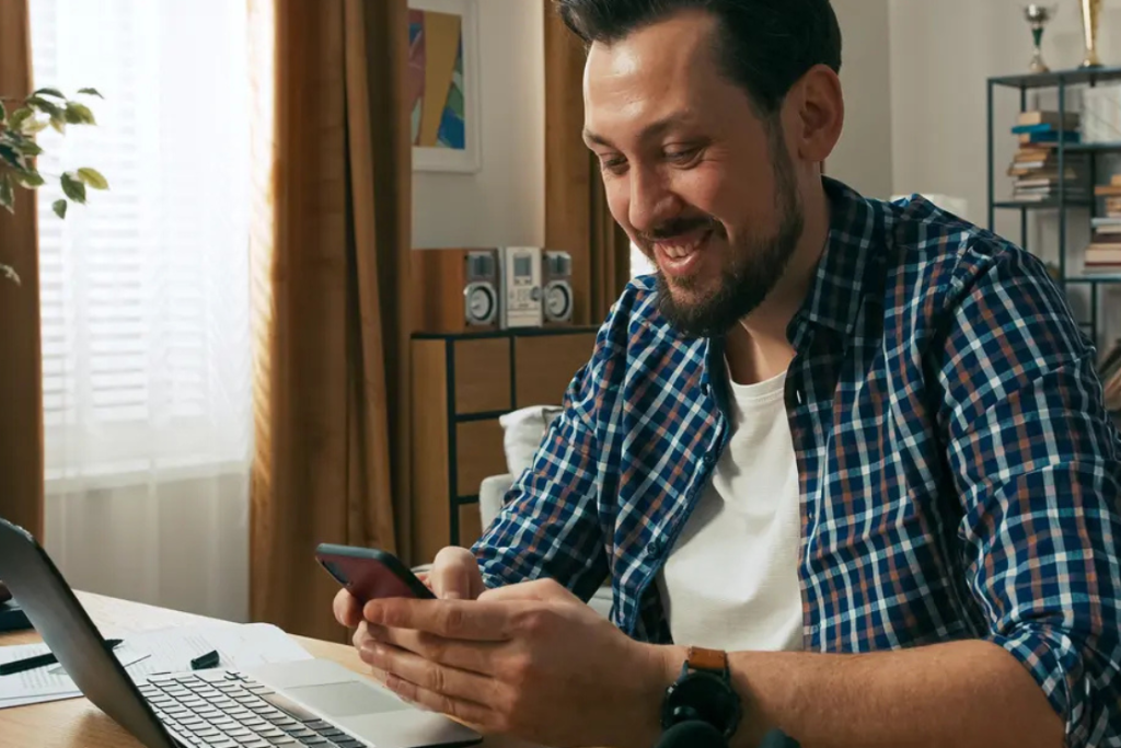 Disabled man smiling while looking at phone while making a referral with My Easy Living