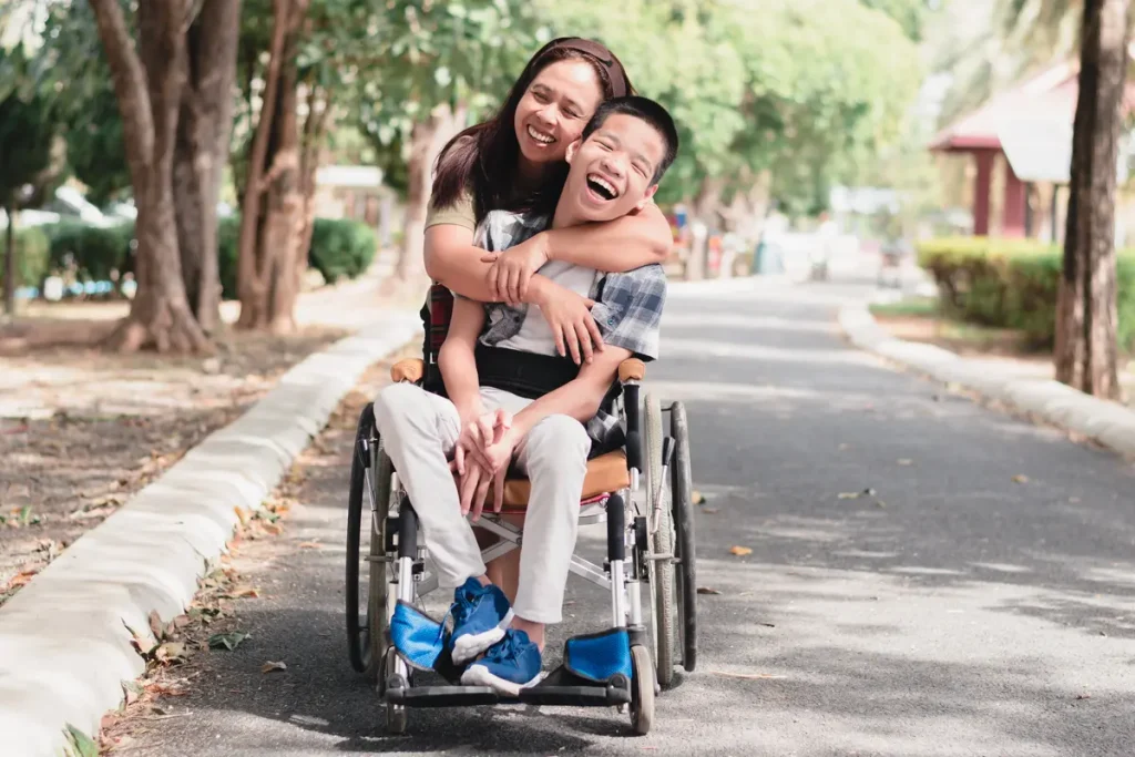 Disabled boy in a wheelchair at the park with his female support worker